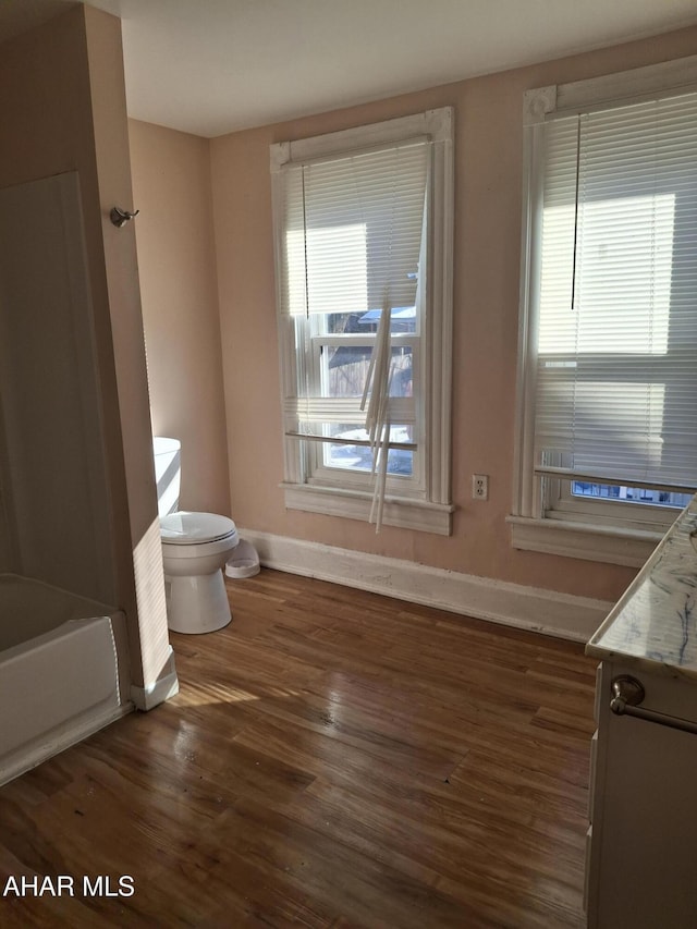 bathroom with vanity, a tub, hardwood / wood-style floors, and toilet