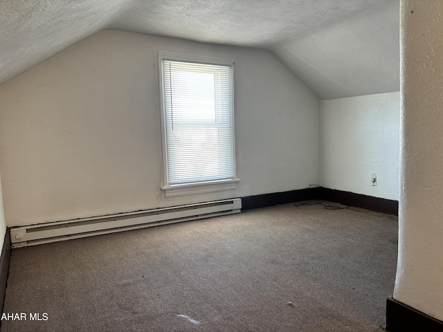 additional living space featuring a textured ceiling, vaulted ceiling, and baseboard heating