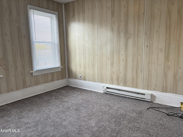 spare room featuring carpet flooring, a baseboard radiator, and wood walls