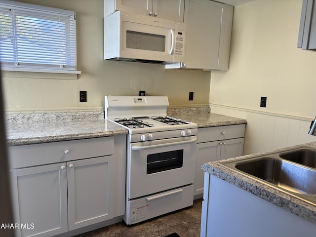 kitchen featuring light stone counters, sink, and white appliances