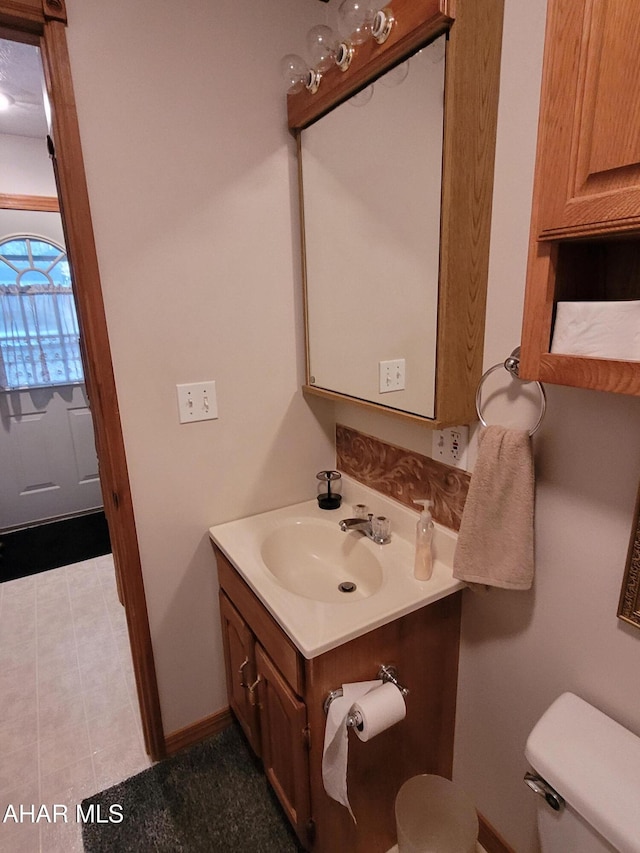 bathroom with toilet, vanity, and baseboards