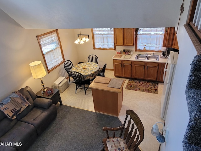 kitchen with pendant lighting, light countertops, brown cabinets, a notable chandelier, and a sink