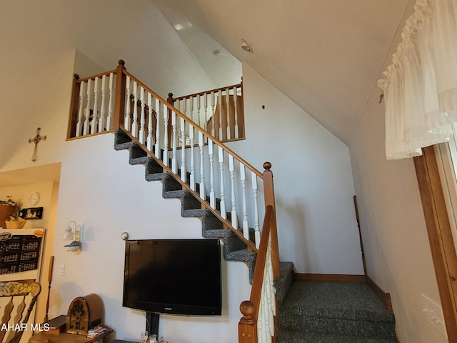 stairs with high vaulted ceiling and baseboards