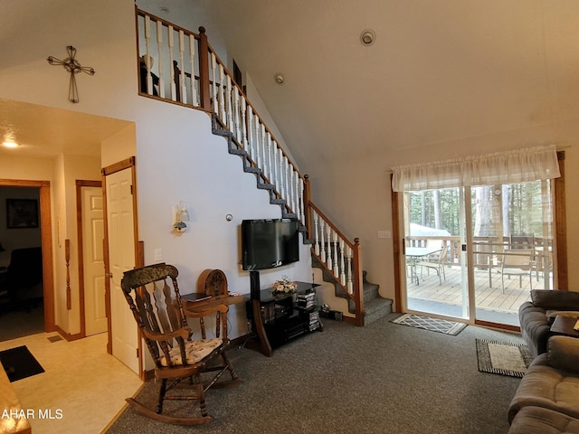 living area with stairway, carpet flooring, and a towering ceiling