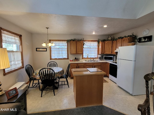 kitchen with stainless steel microwave, brown cabinets, freestanding refrigerator, stove, and a sink