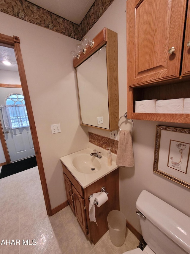 bathroom featuring baseboards, toilet, and vanity