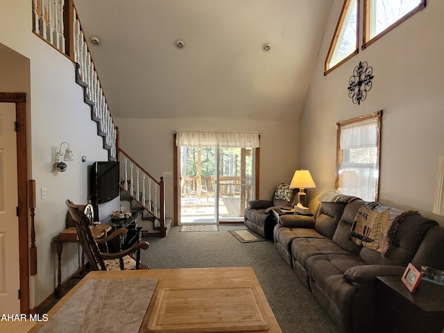 carpeted living area featuring high vaulted ceiling and stairs