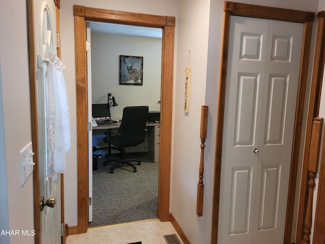 office with baseboards, visible vents, and light carpet