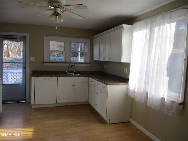 kitchen featuring dark countertops, a sink, light wood-type flooring, and white dishwasher