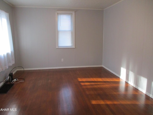 empty room with a wealth of natural light, baseboards, wood finished floors, and crown molding