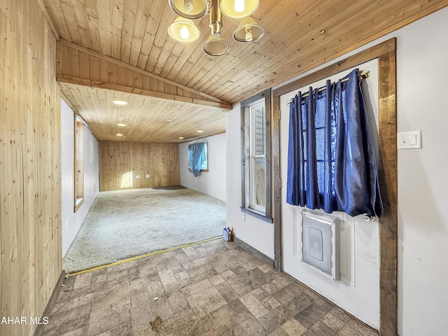 carpeted foyer featuring lofted ceiling, wood walls, and wood ceiling