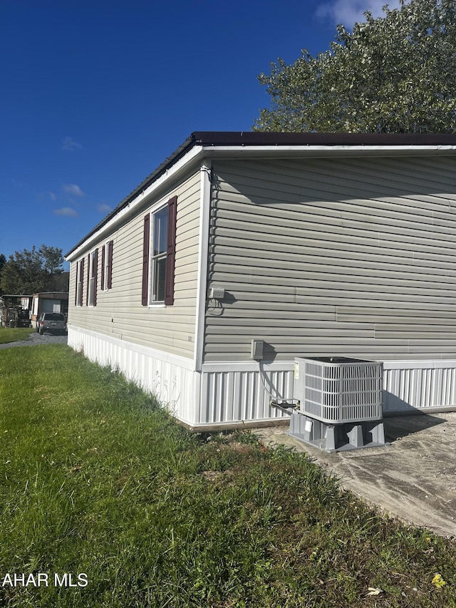 view of side of property featuring a yard and central AC unit