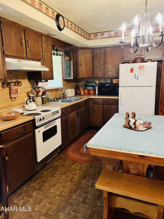 kitchen with dark parquet flooring, white appliances, sink, an inviting chandelier, and hanging light fixtures