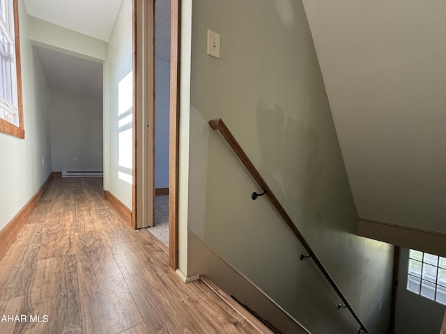 hall featuring lofted ceiling, a baseboard heating unit, and light wood-type flooring