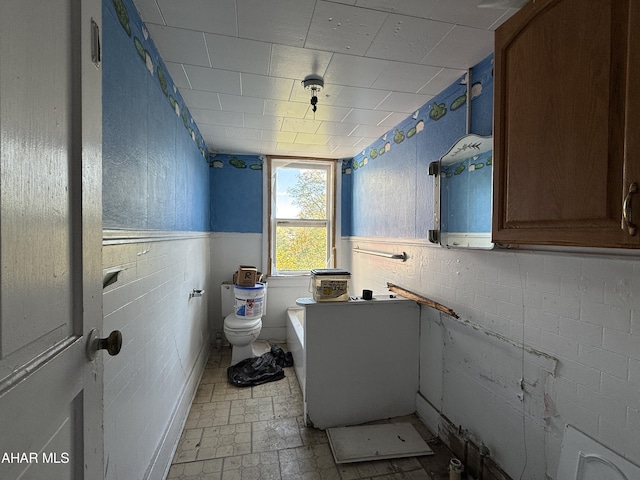 bathroom featuring toilet and tile walls