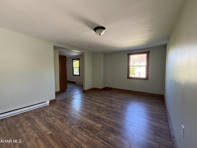 empty room with plenty of natural light, dark wood-type flooring, and a baseboard radiator