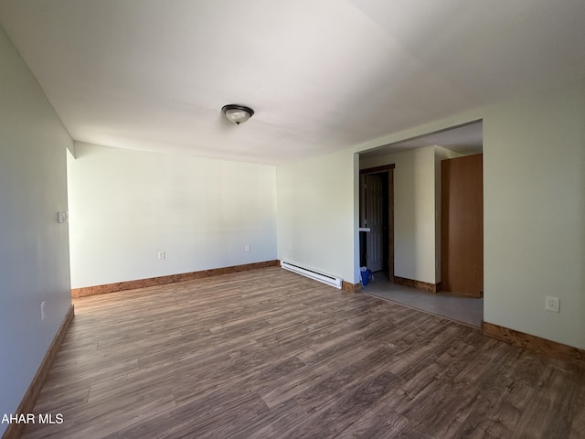 empty room with hardwood / wood-style flooring and a baseboard heating unit