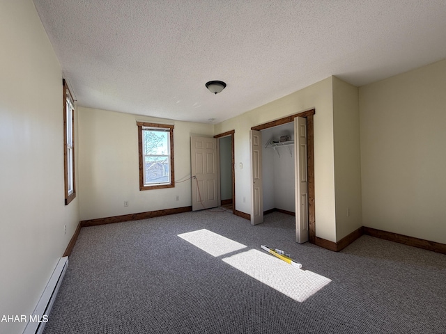 unfurnished bedroom with a textured ceiling, dark carpet, a closet, and a baseboard heating unit