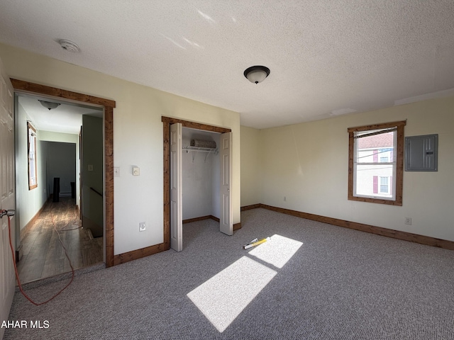 unfurnished bedroom with carpet, a textured ceiling, electric panel, and a closet