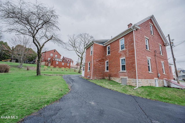 view of side of property with a chimney, a yard, and brick siding