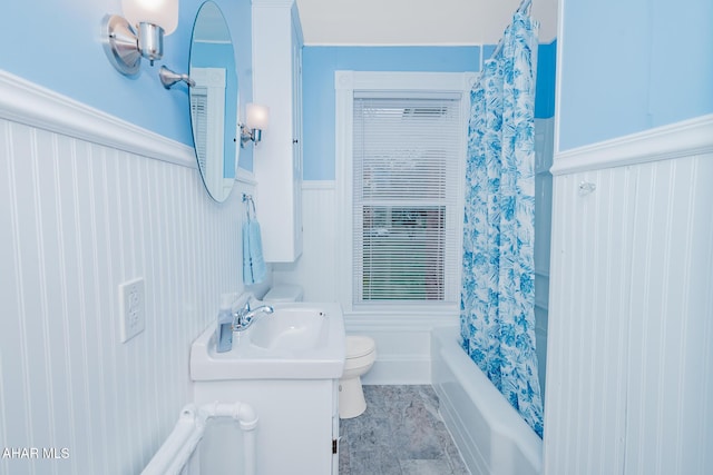 bathroom with wainscoting, toilet, a sink, and shower / tub combo