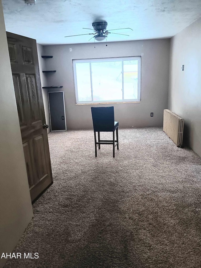 interior space featuring radiator, carpet, and a ceiling fan