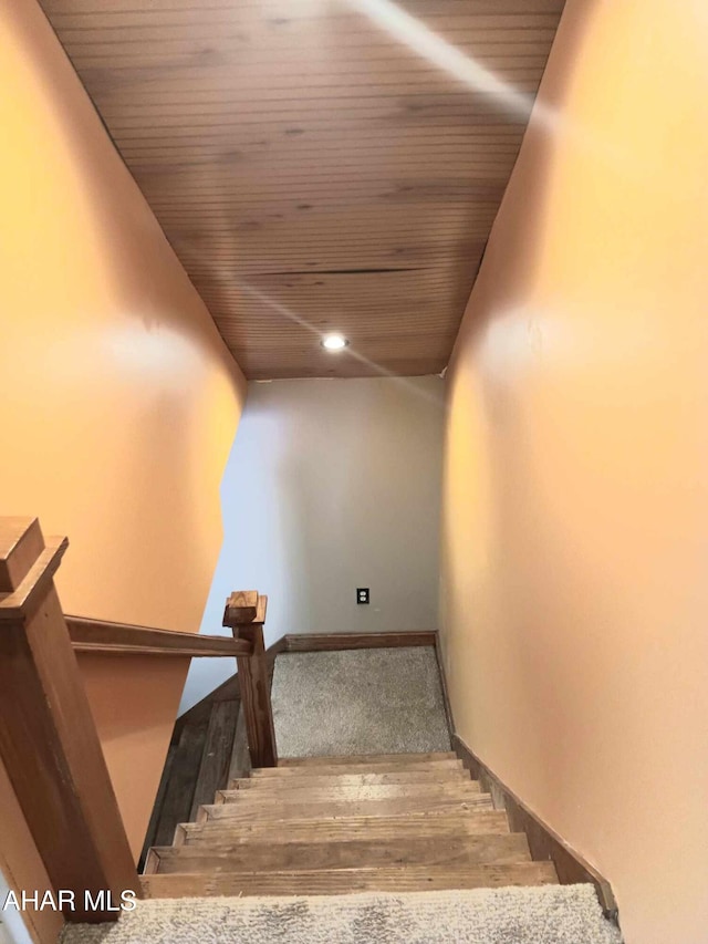 stairs featuring wood finished floors, wood ceiling, and baseboards