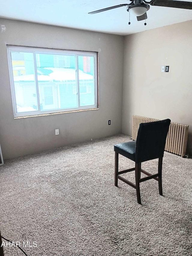 sitting room featuring carpet, radiator heating unit, and a ceiling fan