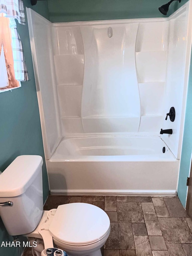 full bath featuring toilet, stone finish floor, and  shower combination