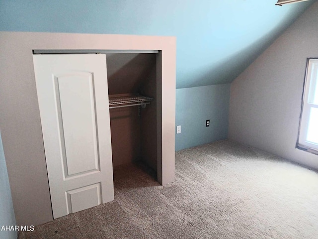 unfurnished bedroom featuring vaulted ceiling, a closet, and carpet