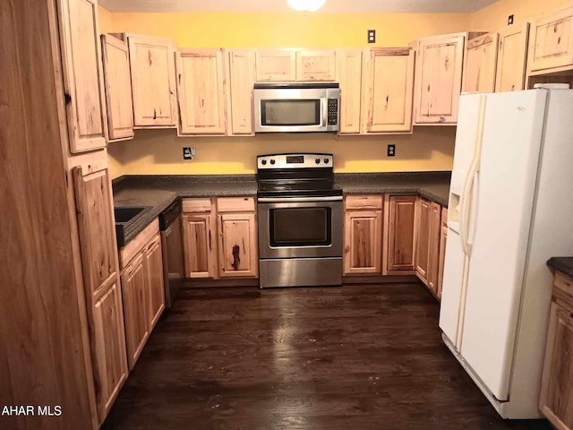 kitchen featuring stainless steel appliances, dark countertops, and dark wood-type flooring