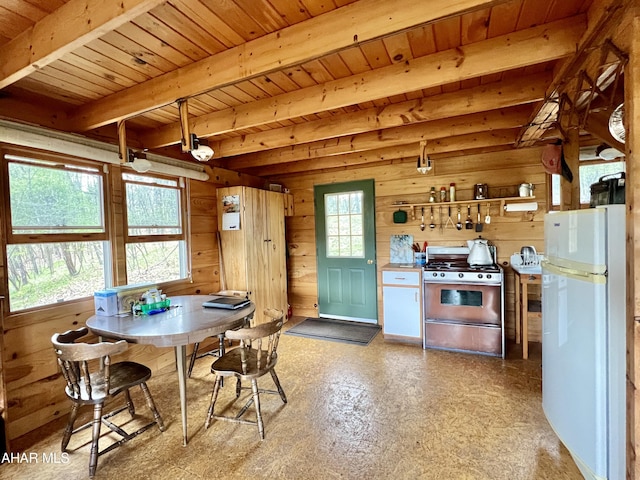 dining space with beam ceiling, wooden walls, and wood ceiling