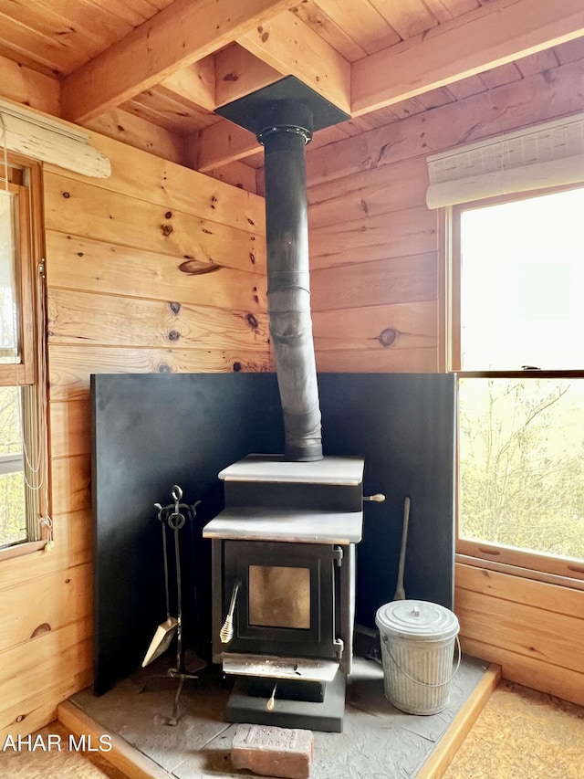 room details with beam ceiling, a wood stove, wooden walls, and wooden ceiling