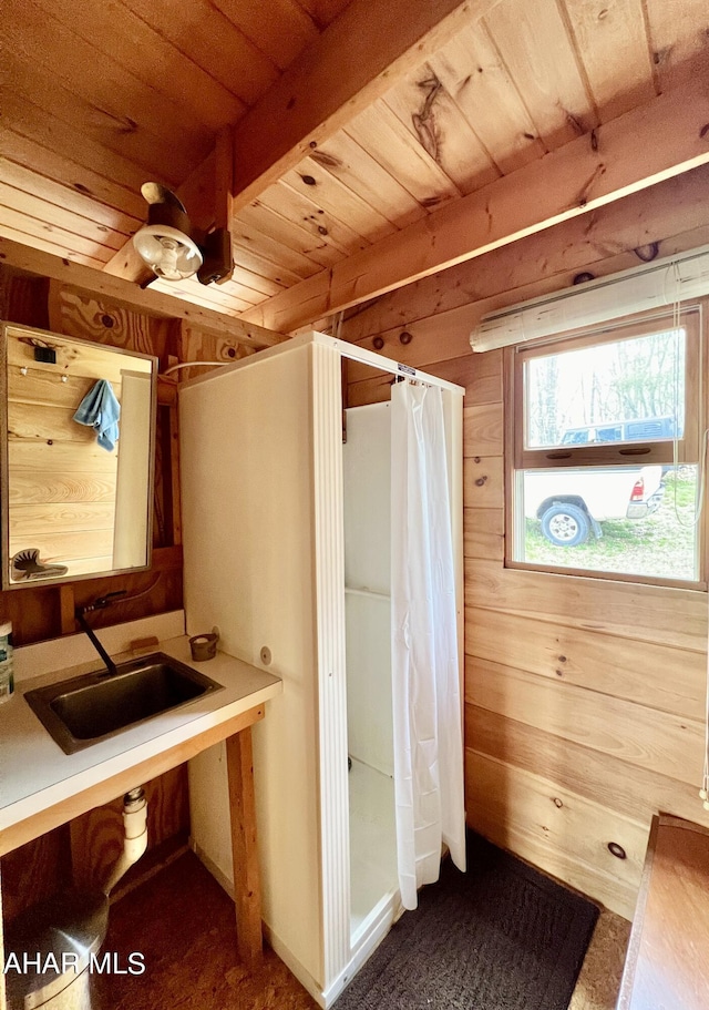 bathroom with beam ceiling, wood walls, wooden ceiling, and sink