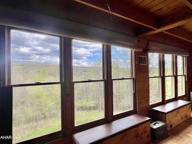 unfurnished sunroom with beam ceiling, wood ceiling, and a healthy amount of sunlight