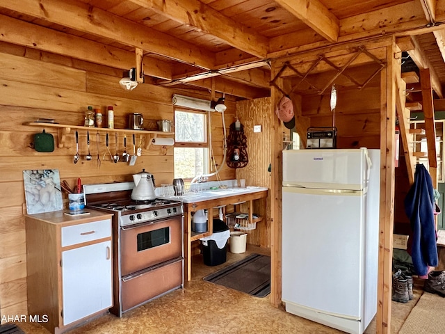 kitchen featuring gas range, wooden walls, white refrigerator, wooden ceiling, and beamed ceiling