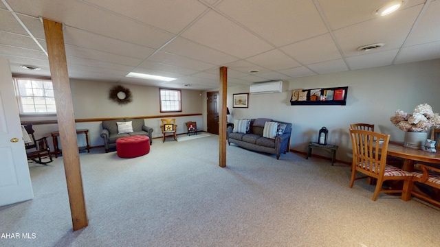 carpeted living room with a paneled ceiling, visible vents, a wall mounted air conditioner, and baseboards