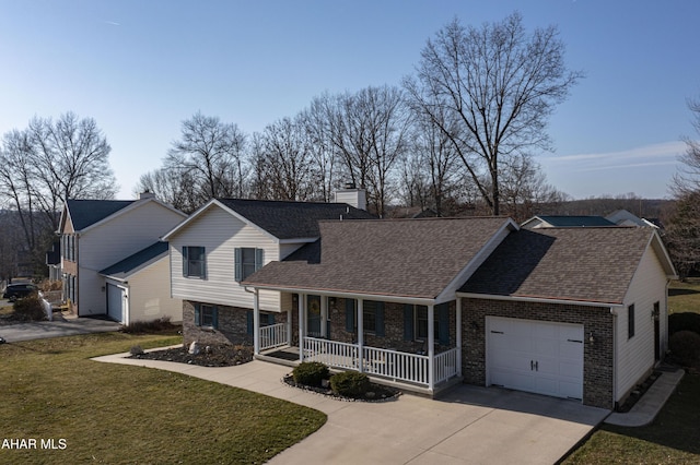 tri-level home featuring concrete driveway, an attached garage, a porch, and a front lawn