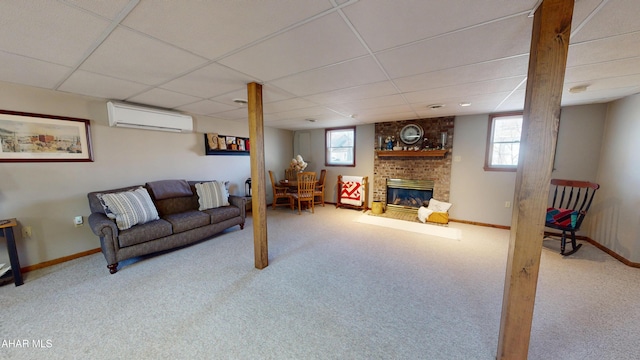 living room featuring a wealth of natural light, a fireplace, an AC wall unit, and a paneled ceiling