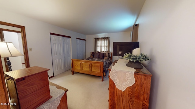 bedroom with light colored carpet and multiple closets