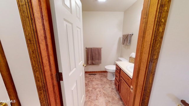 bathroom with vanity, toilet, and baseboards