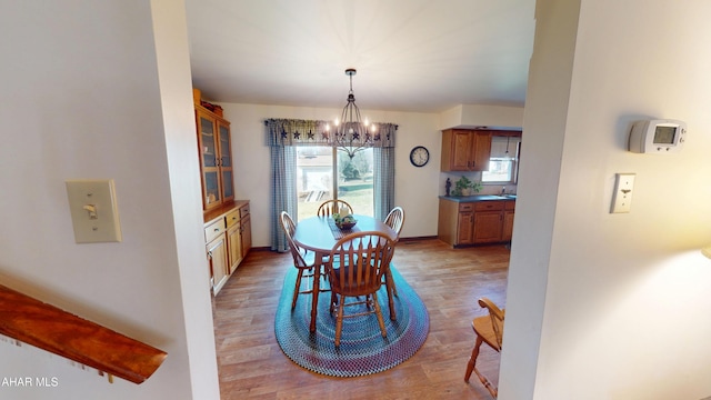 dining room with light wood-type flooring, baseboards, and an inviting chandelier