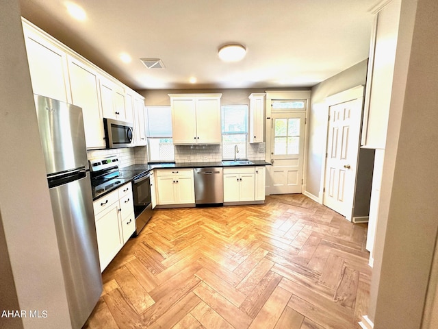 kitchen with decorative backsplash, white cabinetry, sink, and stainless steel appliances