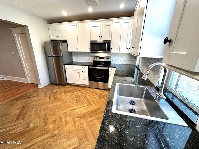 kitchen with white cabinetry, sink, stainless steel appliances, decorative backsplash, and light parquet flooring