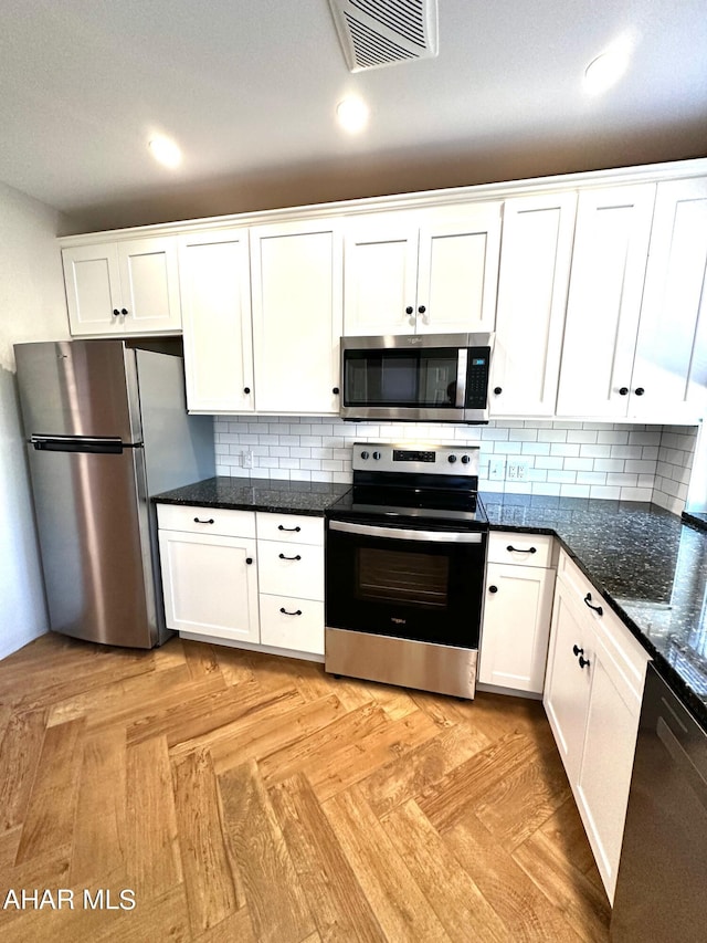 kitchen with white cabinets, appliances with stainless steel finishes, light parquet flooring, and decorative backsplash