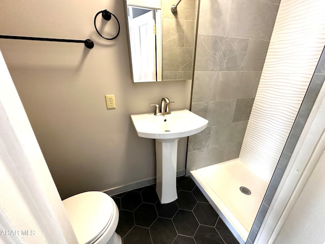 bathroom with tile patterned floors, toilet, and a tile shower