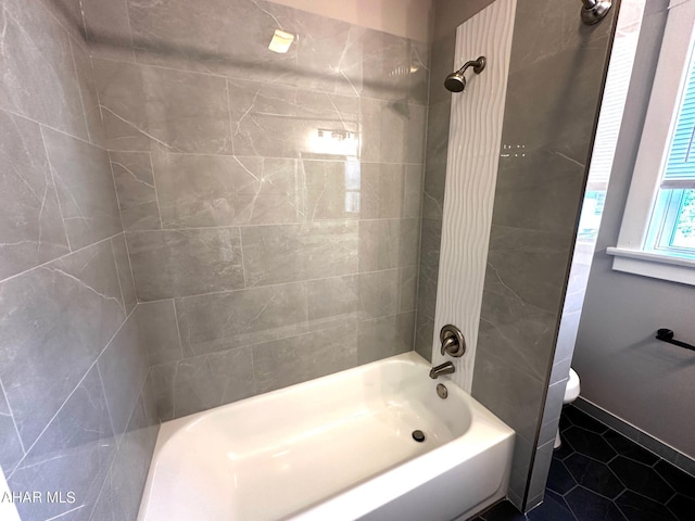 bathroom featuring tile patterned flooring, toilet, and tiled shower / bath