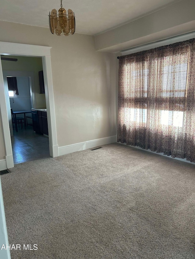 carpeted empty room featuring a notable chandelier