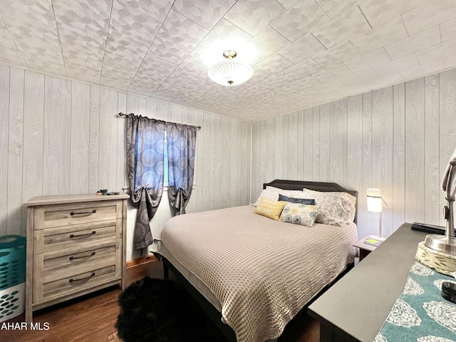 bedroom with dark hardwood / wood-style floors and wood walls