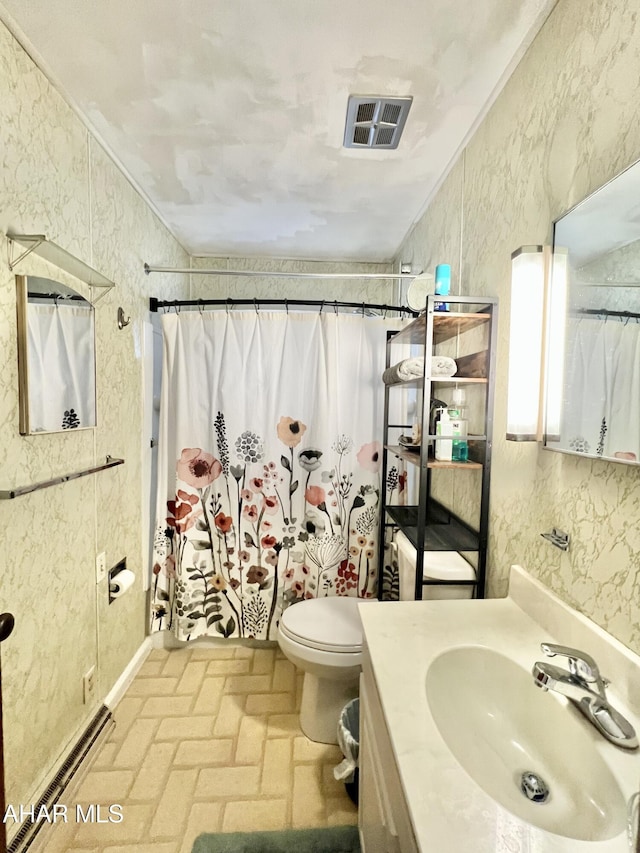 bathroom with vanity, toilet, ornamental molding, and walk in shower